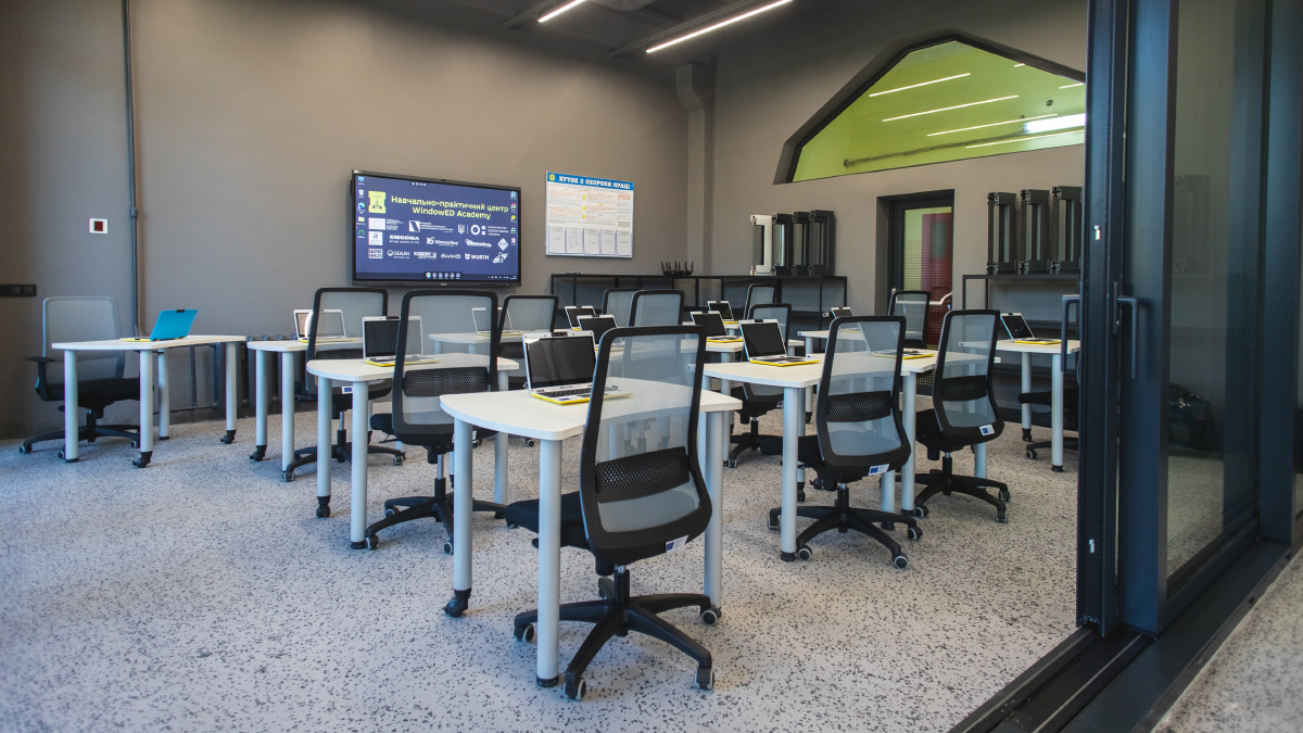 Класс оборудован современной мебелью, включая столы и эргономичные офисные кресла, а также большим интерактивным экраном