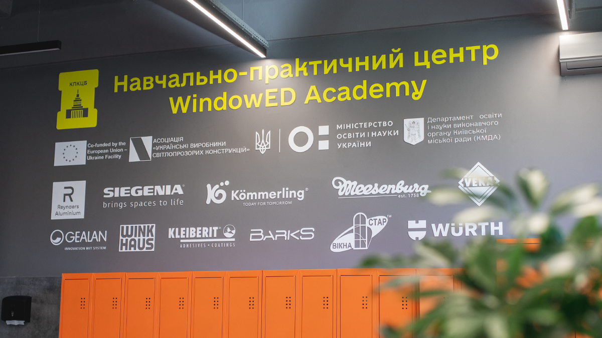 На стене видны логотипы ведущих поставщиков профилей, фурнитуры и комплектующих, таких как Reynaers Aluminium, Siegenia, Kömmerling, Gealan, Winkhaus, Kleiberit, Wurth и других.