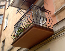 Открытый балкон с коваными гнутыми стойками.
