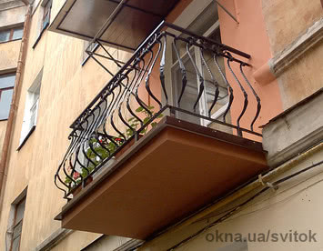 Открытый балкон с коваными гнутыми стойками.